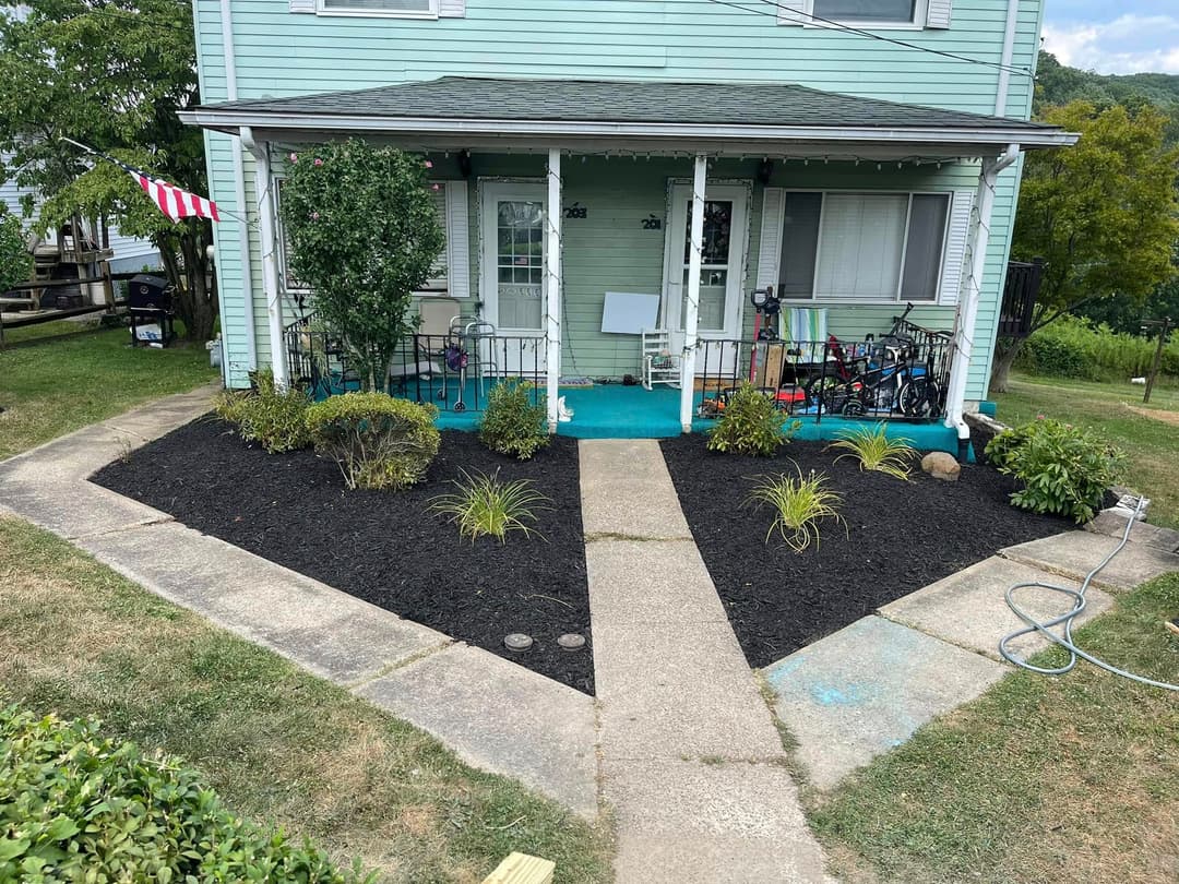 Colorful front yard of a two-story house with landscaped garden and bicycles on the porch.