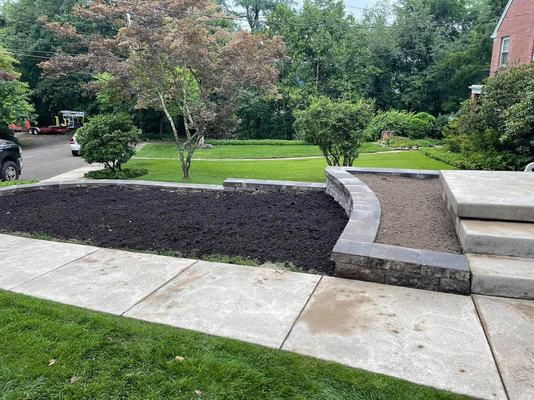 Landscaped yard with new planting beds, stone border, and freshly tilled soil.