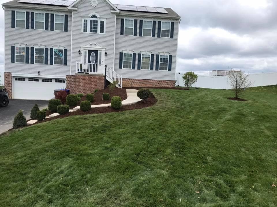 Two-story house with solar panels, landscaped yard, and well-maintained grass.