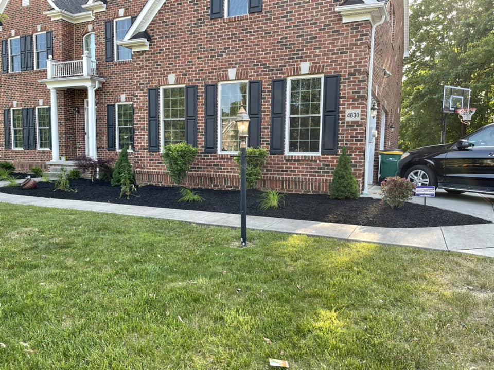 Brick house with black shutters, landscaped yard, and basketball hoop in driveway.