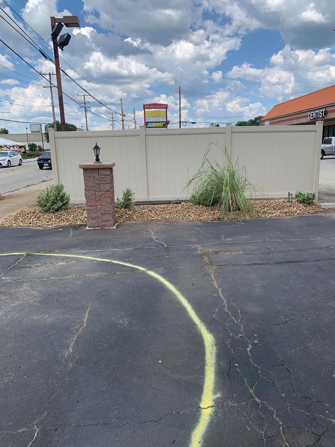 Sign for Subway restaurant beside a dentist office, with blue sky and clouds above.