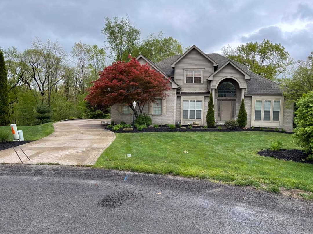 Modern suburban home with landscaping and colorful trees on a cloudy day.