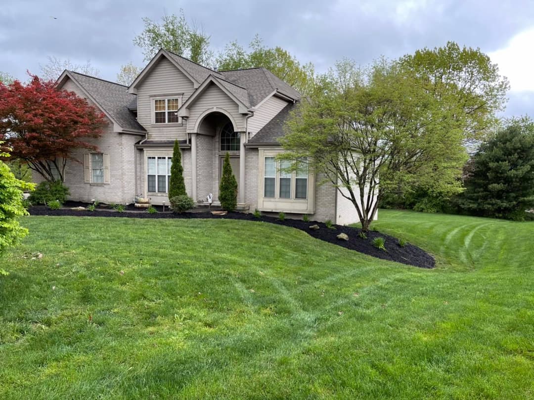 Modern suburban home with landscaped yard and lush green lawn under cloudy sky.