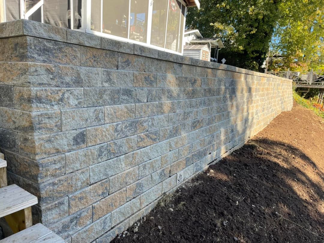 Newly constructed stone retaining wall with rustic gray blocks and landscaped garden.