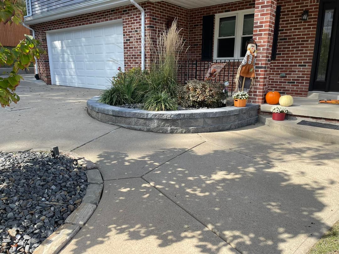 Colorful autumn decorations by a brick home entrance with plants and pumpkins.