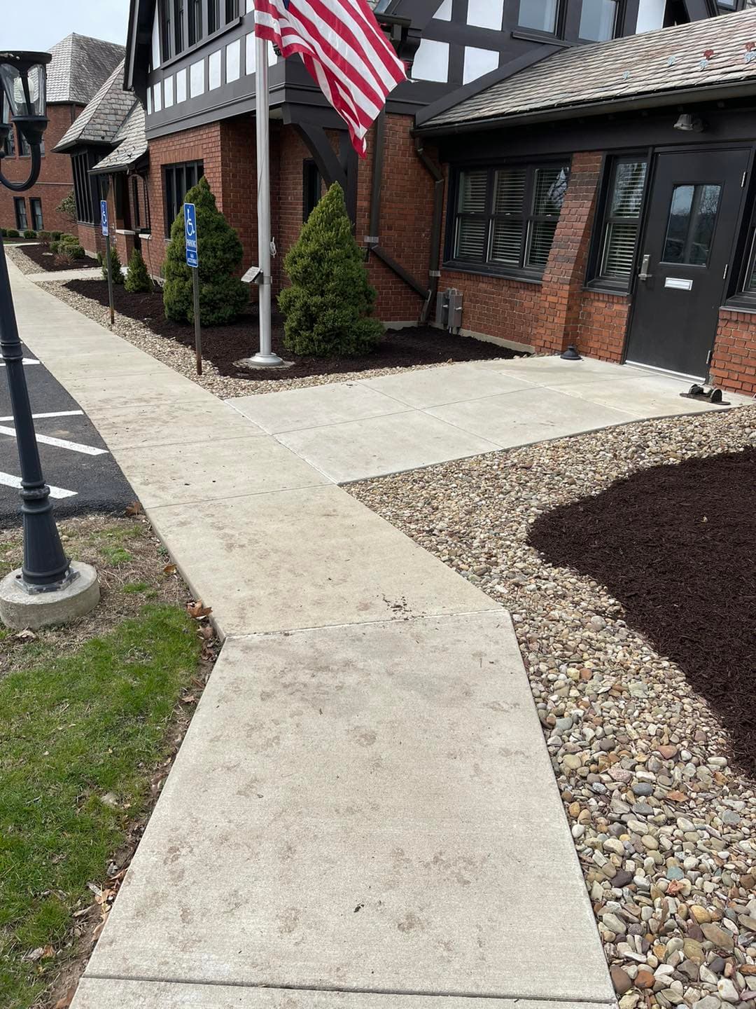 Walkway leading to a brick building with an American flag and landscaped edges.