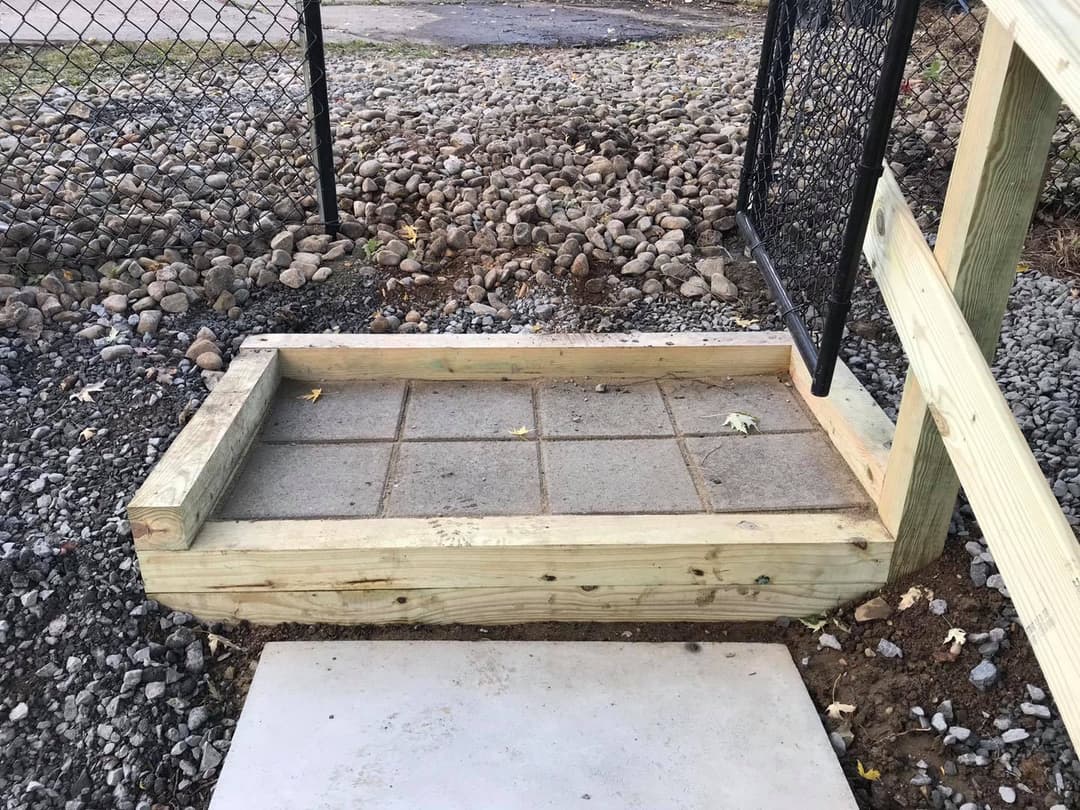 Wooden framework for a stone pathway entrance with gravel background and gate.