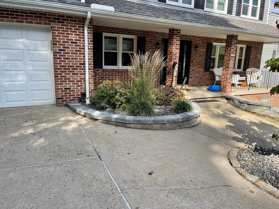 Front entrance of a brick house featuring landscaped flower beds and a curved stone border.