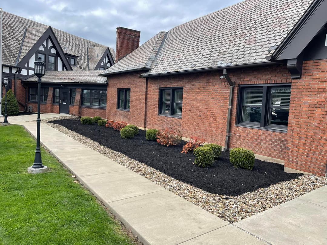 Brick building exterior with manicured landscaping, shrubs, and walking path.