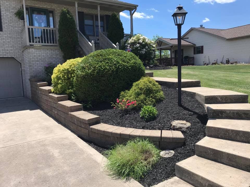 Lush garden landscaping with stone steps and light fixture, featuring colorful flowers and shrubs.