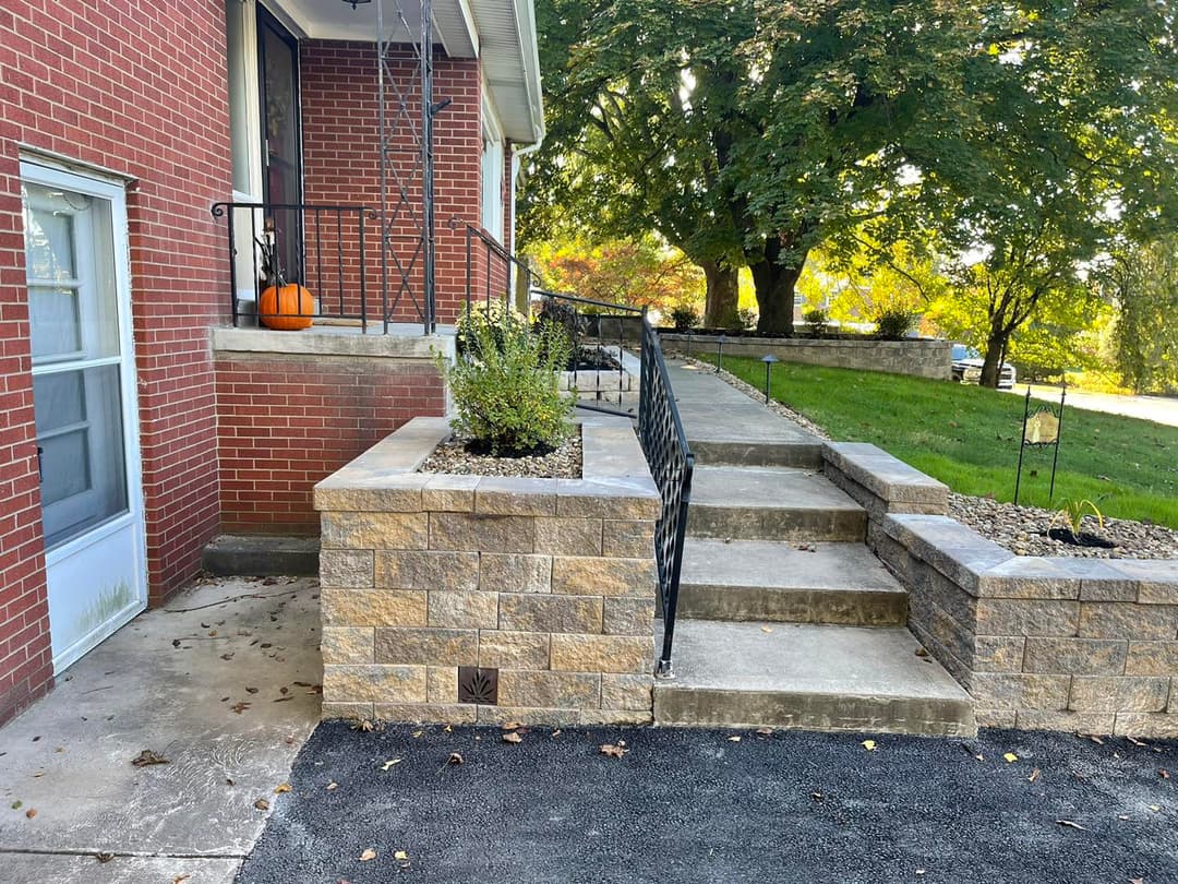 Stone steps lead to a house entrance, surrounded by greenery and seasonal decorations.