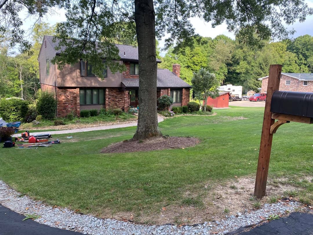 Modern brick home with landscaped yard, bordered by a circular driveway and mailbox.