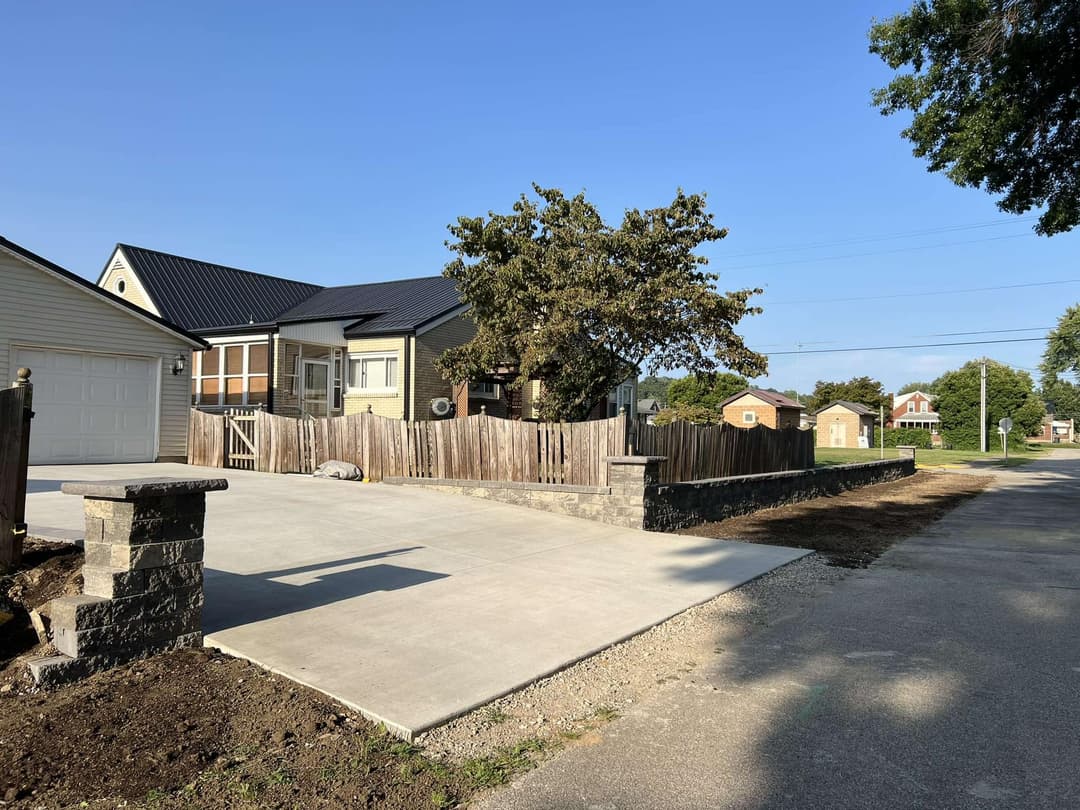 Residential property with concrete driveway, wooden fence, and clear blue sky.