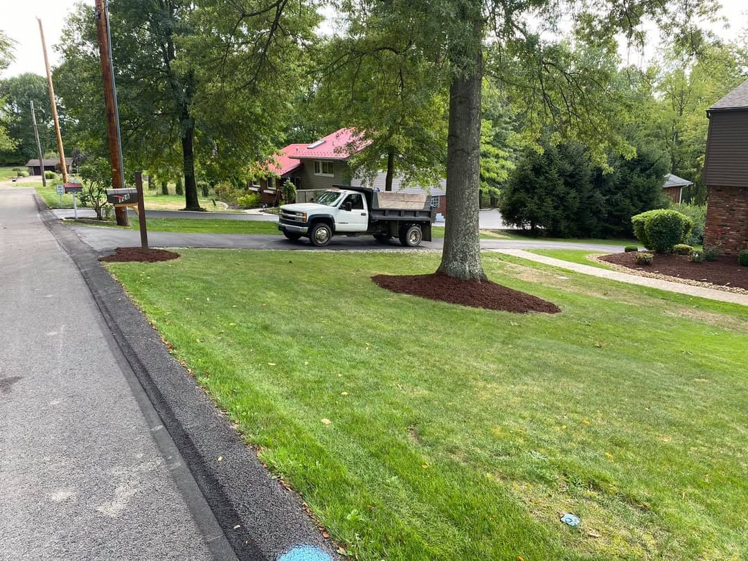 Pickup truck delivering mulch in residential neighborhood with manicured lawns.