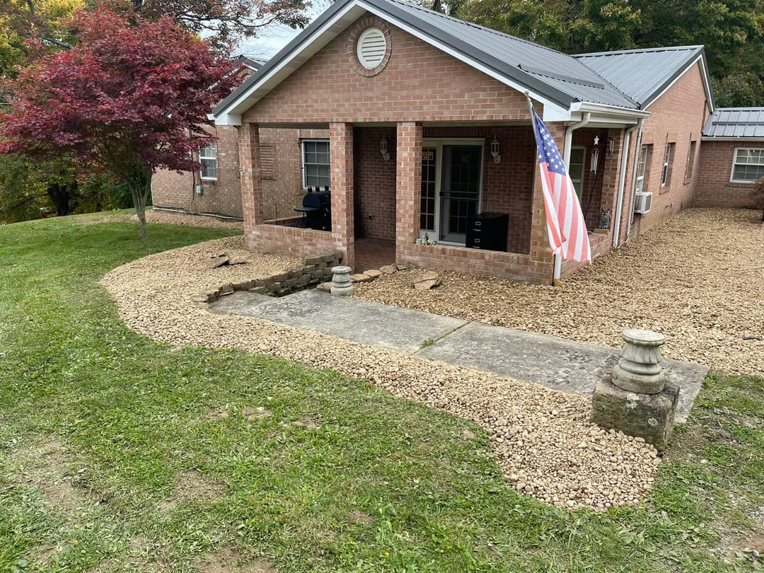 Brick home with American flag, gravel walkway, and landscaped front yard.