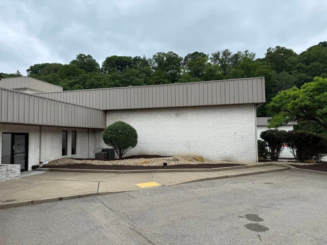 Modern building exterior with landscaping and trees, situated in a serene, green environment.