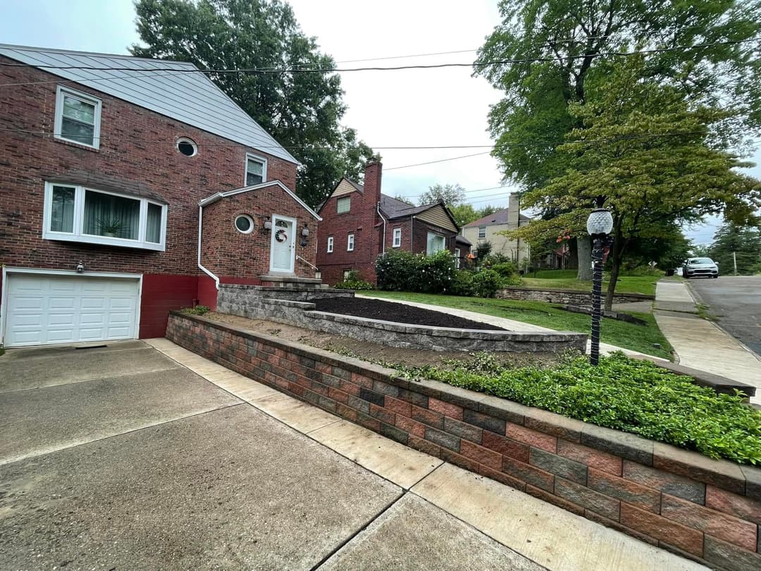 Brick house with garage and landscaped front yard on a quiet residential street.