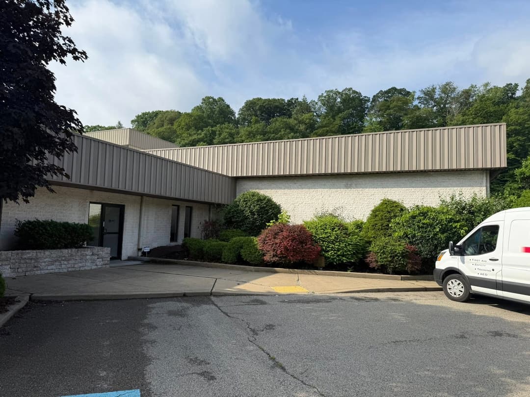 Office building with landscaped grounds and delivery van parked in front.