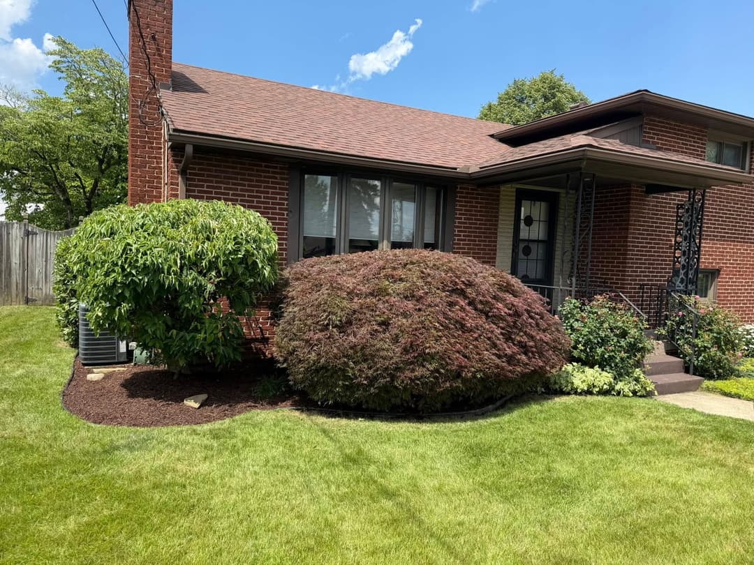 Charming brick house with landscaped front yard and colorful shrubs on a sunny day.