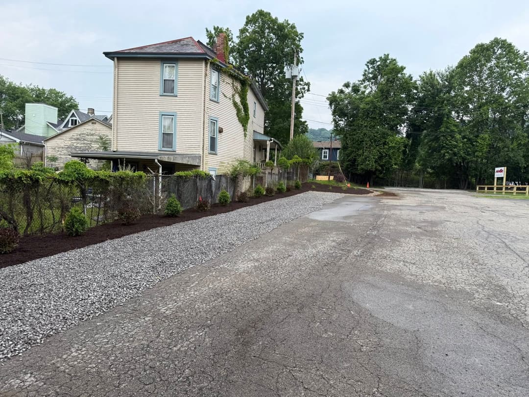 Exterior view of a renovated house beside a gravel driveway and landscaped garden area.