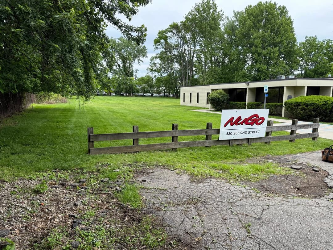 NIGo sign in front of a grassy area and building at 520 Second Street, surrounded by trees.