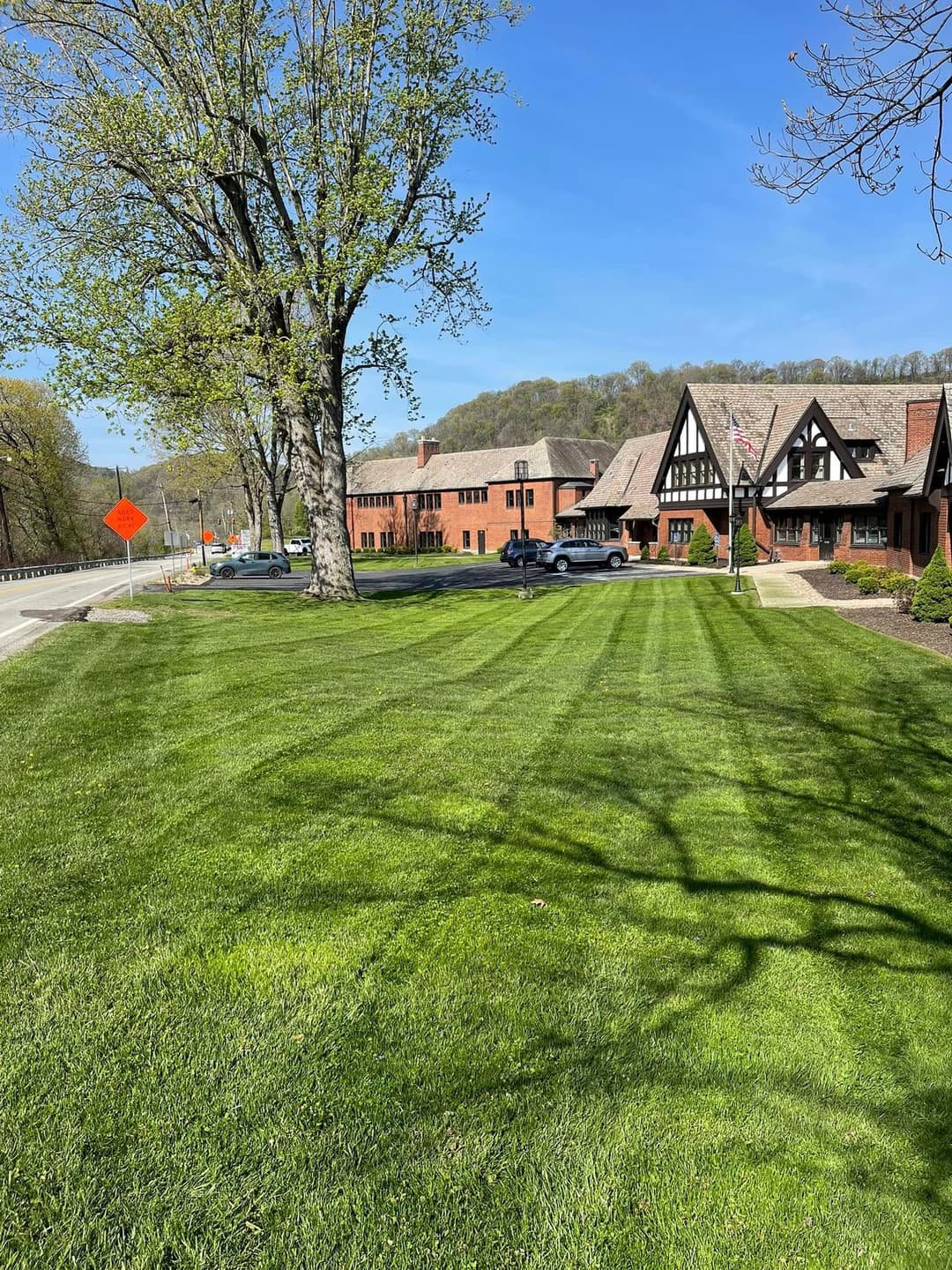 Lush green lawn with manicured stripes outside a historic building on a sunny day.
