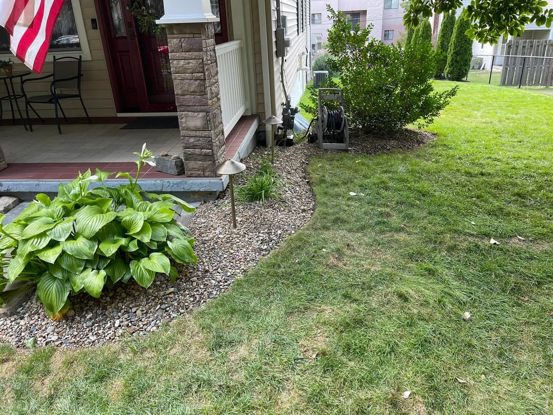 Lush green lawn with landscaped garden featuring hostas and decorative outdoor lighting.
