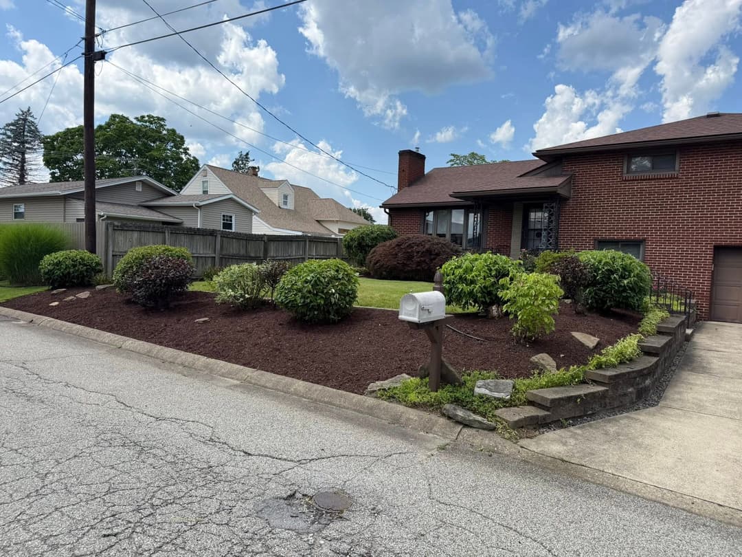 Brick house with landscaped yard, mailbox, and clear blue sky in background.
